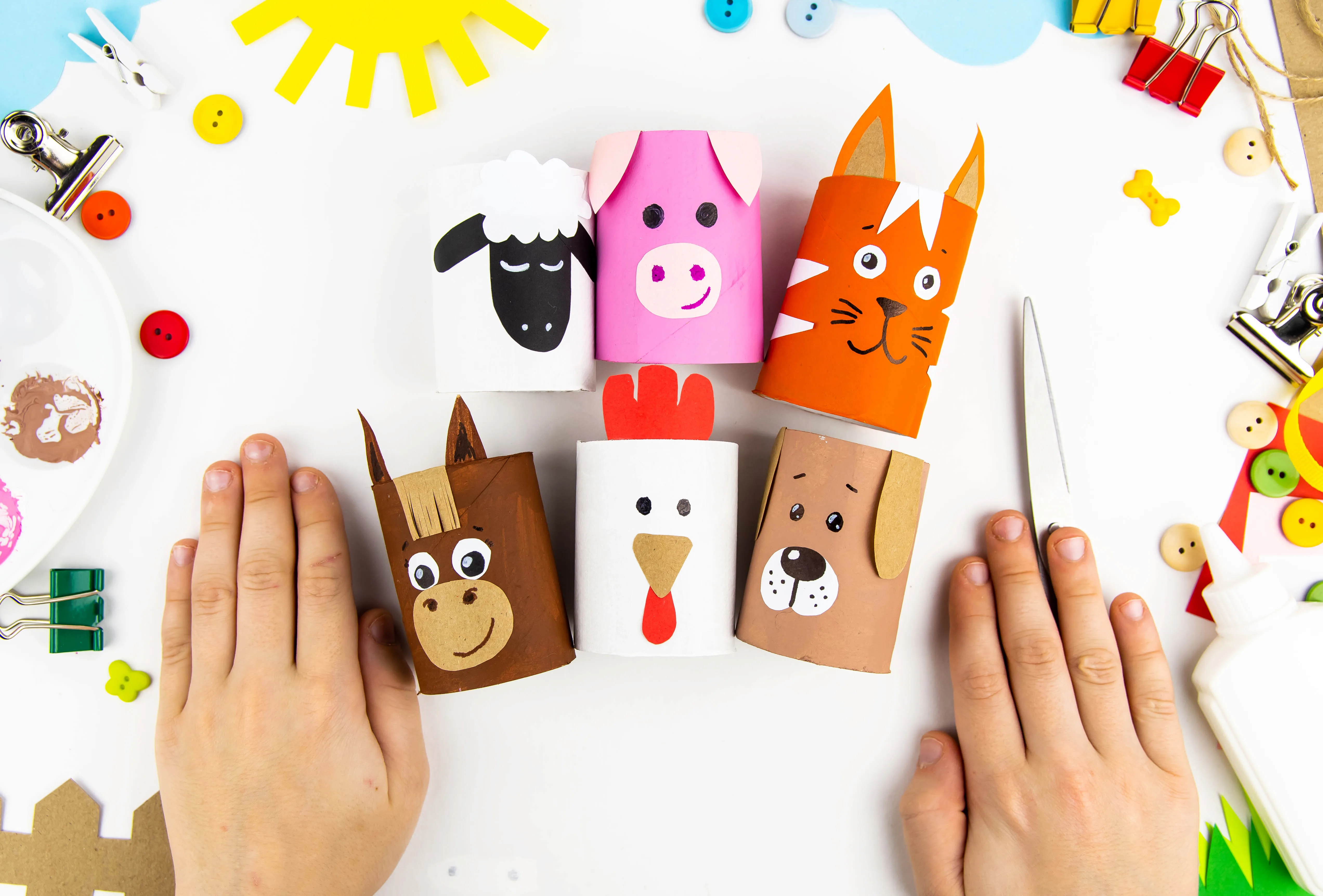 A child's hands making animal figures out of paper craft materials