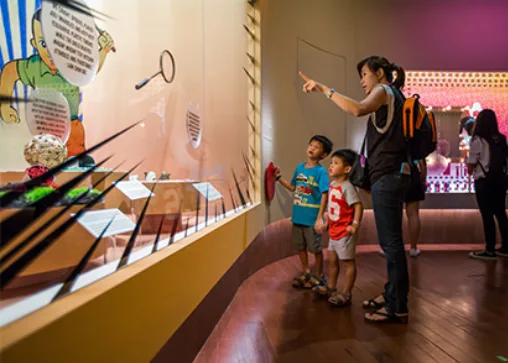 A parent and children looking at wall exhibits in a museum gallery