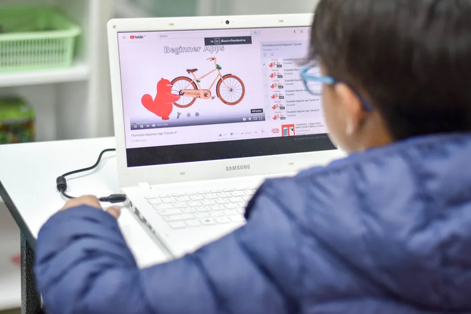 A child at a laptop showing a colourful on-screen design project