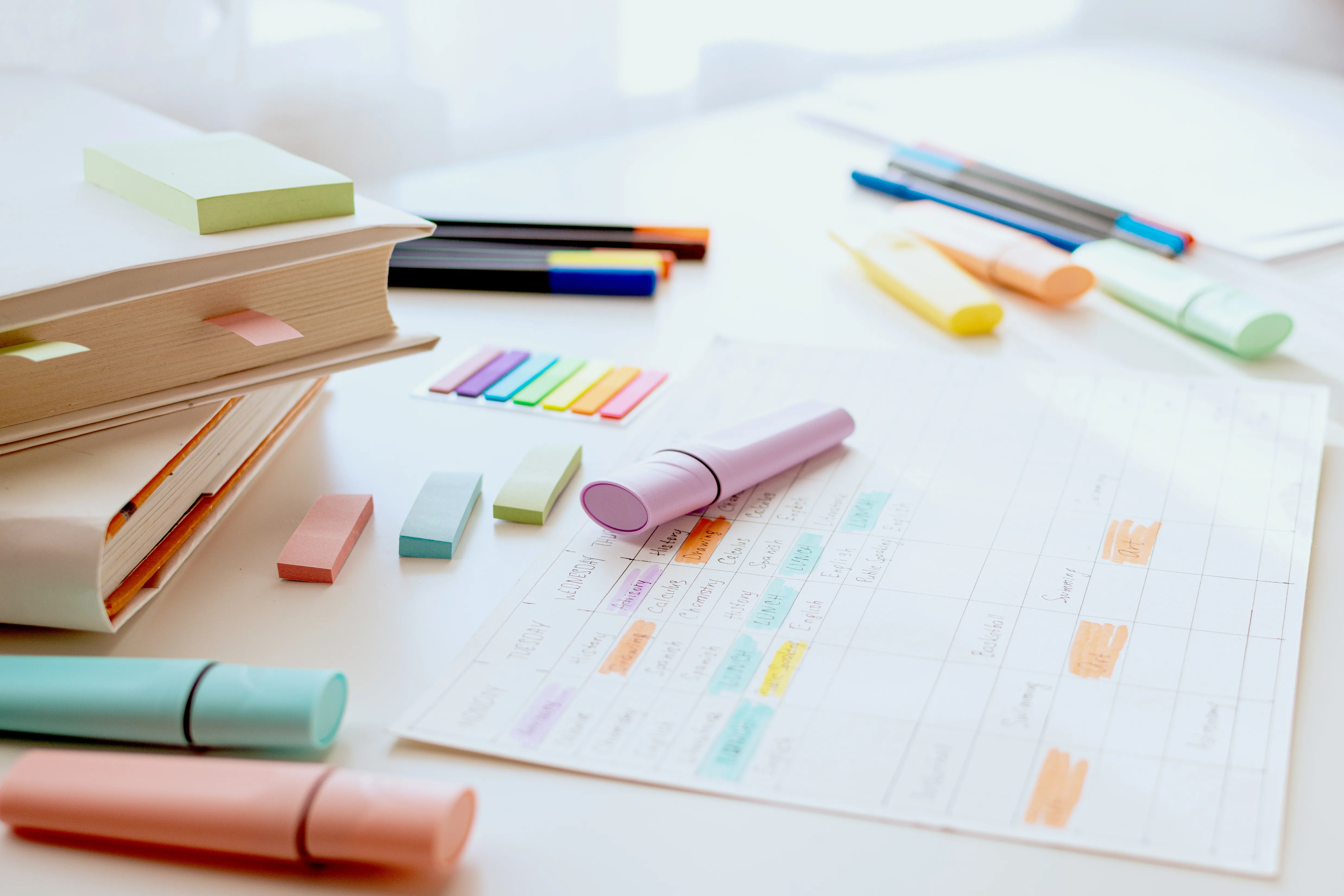 Highlighters, sticky tabs and a planner laid out on a desk