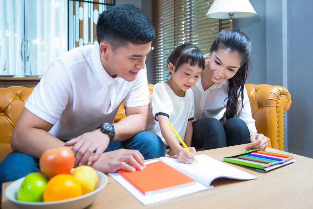 Parents and a child looking at a book together at a table